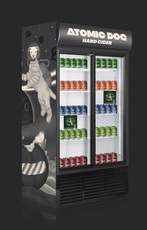 Atomic Dog Hard Cider branded retail cooler stocked with colorful cider cans, featuring a space-themed dog astronaut campaign illustration.