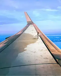 View from airplane wing during flight for Sun Country Airlines brand campaign with surfer