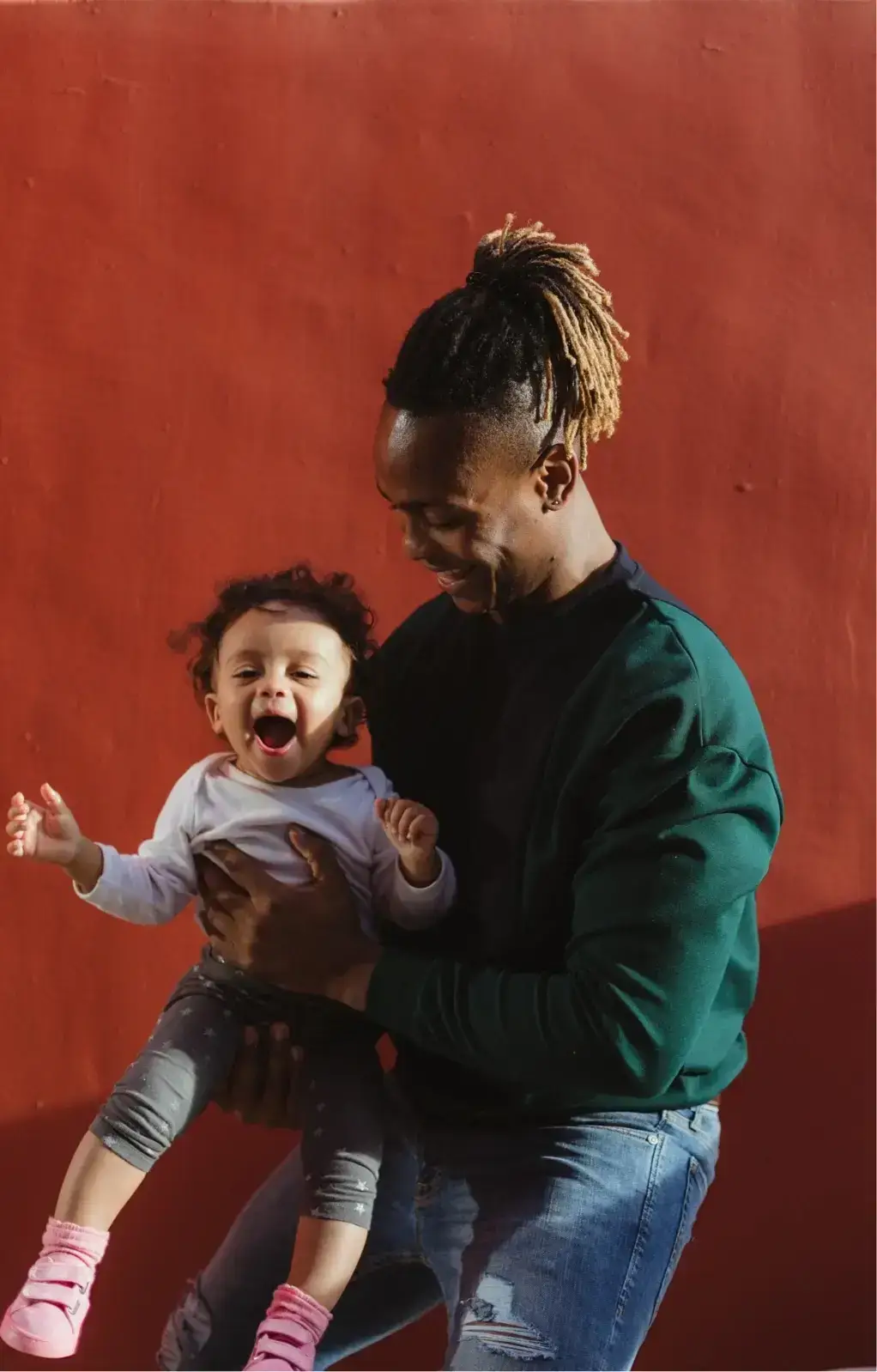 Think Small family photo showing a smiling father holding his young child, representing early childhood support and family connection.