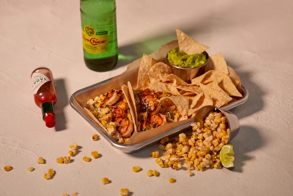 Rubio’s Coastal Grill shrimp tacos with tortilla chips, guacamole, street corn, and bottled drinks, photographed for restaurant brand marketing by Agency Squid.
