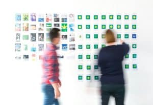 people standing at a white wall with post it notes